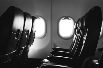 Fototapeta premium Black and white photo of airplane seat and window inside an aircraft
