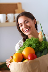 Young woman holding grocery shopping bag with vegetables