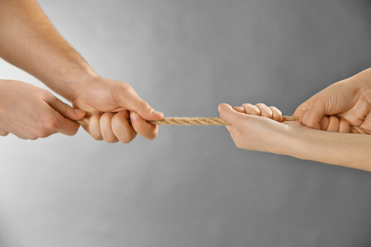 Teamwork concept. People hands pulling the rope on grey background