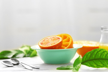Juicy oranges in blue bowl on white table