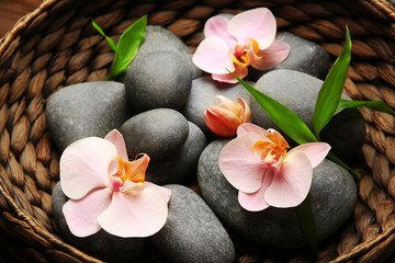 Fototapeta na wymiar Spa stones and orchid flowers in wicker basket