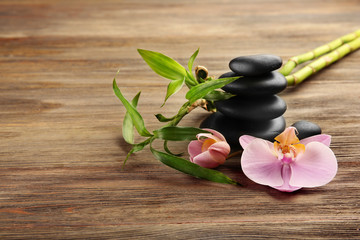Spa stones, bamboo sticks and orchid flowers on wooden background