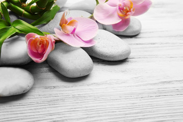 Naklejka na ściany i meble Spa stones, bamboo stack and orchid flowers on wooden background