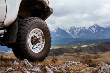 Big car wheel is standing on the rocks on mountain backdrop. Altay mountains, Siberia, Russia © cppzone