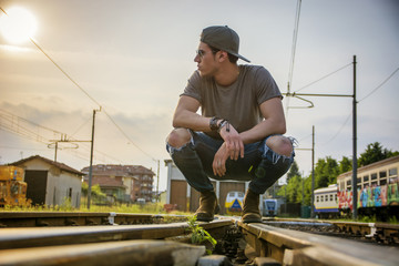 Attractive young man sitting on railroad