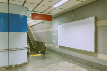 Blank billboard beside escalator in subway. Useful for your adve
