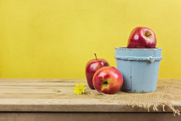 Apples on wooden table over yellow wallpaper background