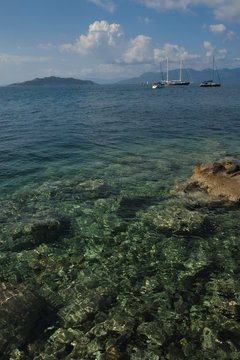 Transparent Greek Sea with boats amd island views.
