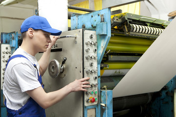 Man in cap working in newspaper factory