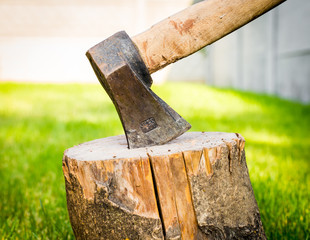 Old rusty ax stuck in a dry wooden log