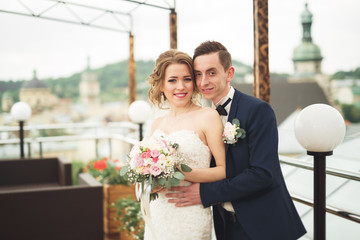 Happy wedding couple, bride, groom kissing with view of old city