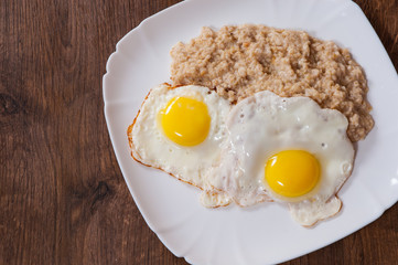 oatmeal porridge with fried egg in a plate on wooden table