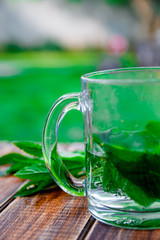 A cup of mint tea on a wooden background, closeup. Herbal tea with fresh mint leaves on table