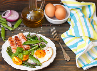 Traditional breakfast - fried eggs, sausages, bacon, asparagus bacon, asparagus, tomato, beans, green peas, onions, Basil
