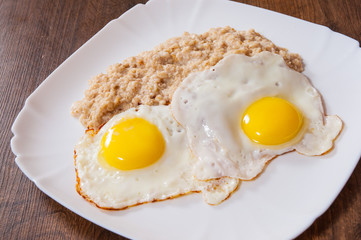 oatmeal porridge with fried egg in a plate on wooden table