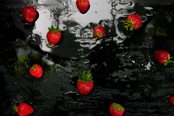 Whole strawberries on black background with water drops. Wet strawberries