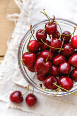 Obraz na płótnie Canvas Fresh juicy sweet cherries in glass bowl. Rustic background with homespun napkin.