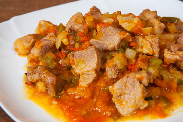 Stewed meat with vegetables in a plate on wooden table