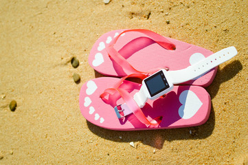 Closeup on smart watch and flip-flops on beach background. Top view style, photo and video outside