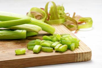 rhubarb stalks, sliced pieces and spirals from the peel on a wooden kitchen board