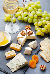 Glass of white wine and assorted cheese with grape