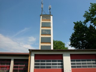 Feuerwehrstation mit roten Segmentieren, Industrietoren und altem Schlauchturm als Sendemast für...