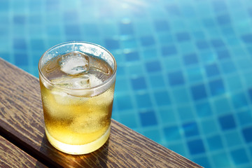 A short glass of ice beer at pool with vintage filter background