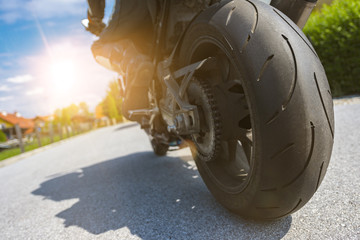 Naklejka premium On the road-biker and his motorbike driving into the evening sun