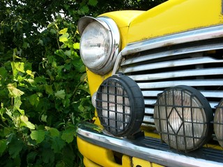 Gelber englischer Kleinwagen im Rallyetrimm der Sechziger Jahre mit Zusatzscheinwerfern bei...