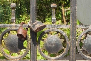 Old rusty lock on a metal gate into the garden. Lock on the iron gate. Symbol imprisonment and slavery. Property security chain. Closed iron gate with a lock. Safe lock.
