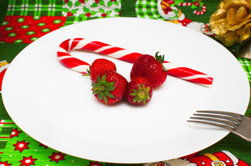 New Year Christmas tablecloth with a pattern of Santa Claus, CHRISTMAS HOLLY, gifts, a fork with a plate of fresh strawberries and candy
