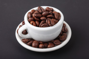 white cup full of coffee beans a gray background