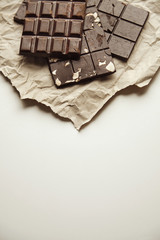 Three different homemade organic natural artisan chocolate bars on rustic craft paper isolated on top on white Space for your text below