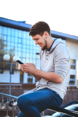 Portrait of a young man in casual clothes with a phone on the background of the business center. The informal business, free business concept