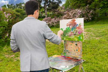 Back view of a male artist painting a beautiful sketch of pictur