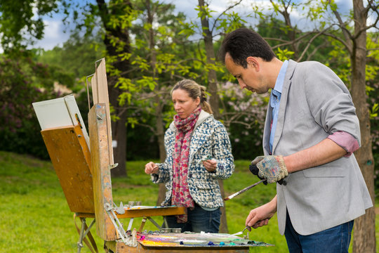 Two middle-aged dreamy artists during an art class in a garden
