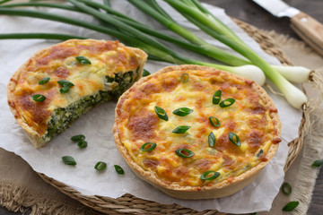 Mini quiche with green onions and cheese on a wooden background 