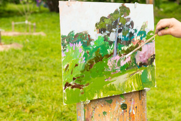 Hand of a painter holding a paintbrush in the open air