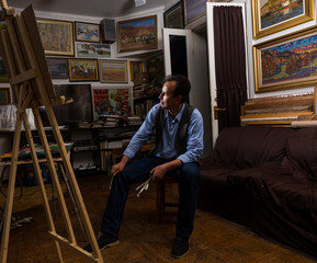 Male artist sitting looking trough his studio