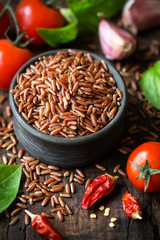 Red rice with various condiments - cherry tomatoes, chili pepper, basil and garlic