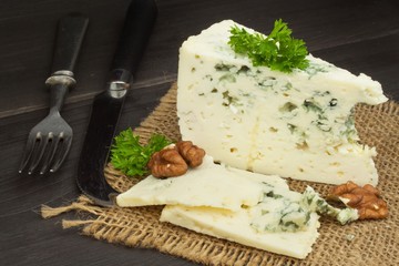Danish blue. Blue cheese close up on an old wooden table. Preparing food blue cheese. Cheese on the kitchen table. Noble rot. Cheese with mold delicacy.
