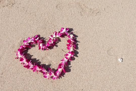 orchid flower garland necklace in love heart shape on white sand beach, romantic couple honeymoon trip at Hawaii 
