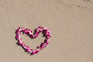 Fototapeta na wymiar orchid flower garland necklace in love heart shape on white sand beach, romantic couple honeymoon trip at Hawaii 