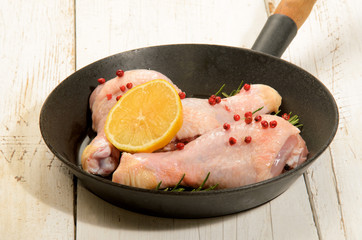 raw chicken drumstick with red peppercorn, lemon slice and rosem
