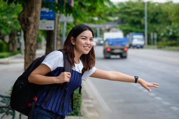 Young woman standing at bus stop on street city. Asian woman waiting for bus. Woman student in private dress standing at bus stop. Public transport stop in Thailand. bus stop on street in asian.