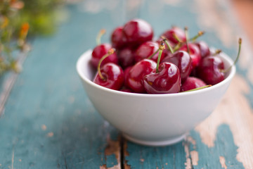 Reife Kirschen in weißer Porzellanschale, auf rustikalem Holz