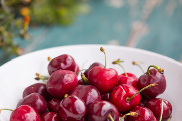 Reife Kirschen in weißer Porzellanschale, auf rustikalem Holz