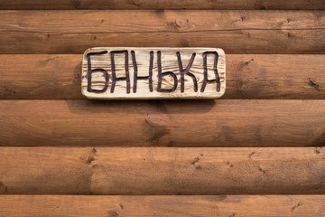 The inscription "bathhouse" on the plate on a wooden background
