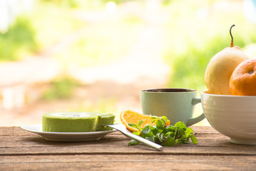 Background fruit in bowl and coffee cup with green tea cake and mint.On wooden background outdoor view and holiday with relax 