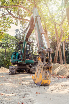 excavator on a construction site against tree and sunlight